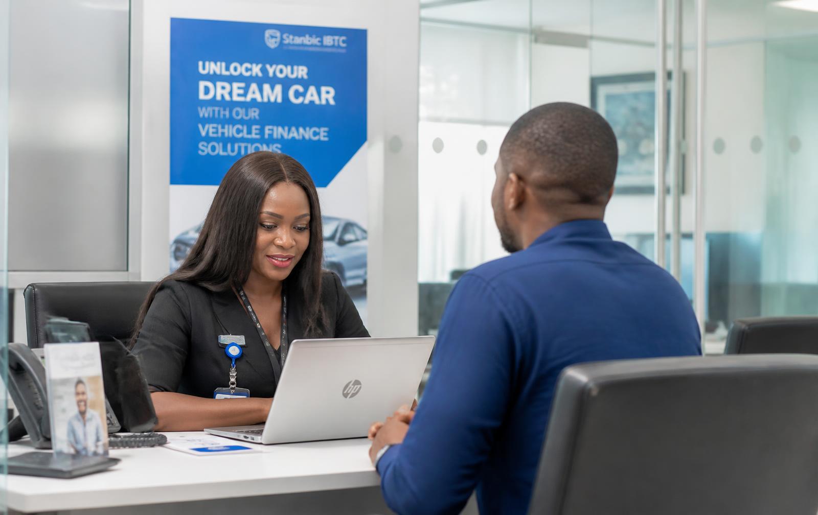 A bank officer in Lagos reviewing an electric vehicle finance application with a customer